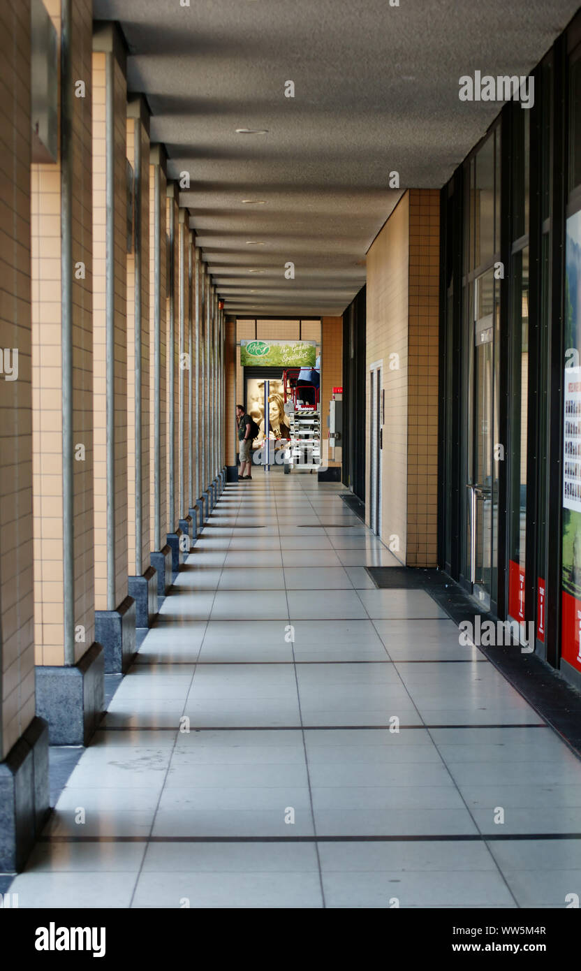 Un homme debout à un kiosque à la gare Kassel derrière une rangée de colonnes en béton, Banque D'Images