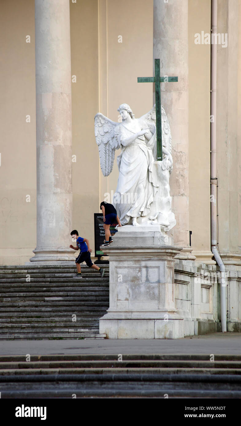 Enfants jouant à l'escalier de l'entrée de l'église de Saint Karl lors d'une sculpture de l'ange à Vienne, Banque D'Images