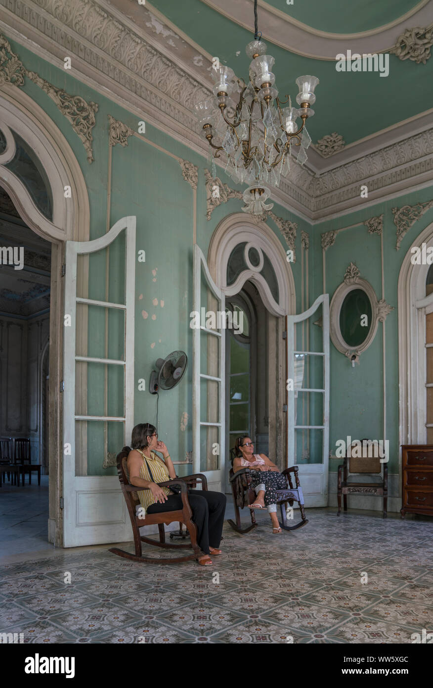 Palacio Ferrer a été construit en 1917-1918 par l'espagnol squire JosÃ© Ferrer, aujourd'hui, le bâtiment est ouvert pour le public, l'image montrant un prix de l'Palacio avec aménagement intérieur et deux préposés 'Museum' dans le rocking chair, Cienfuegos, Cuba Banque D'Images