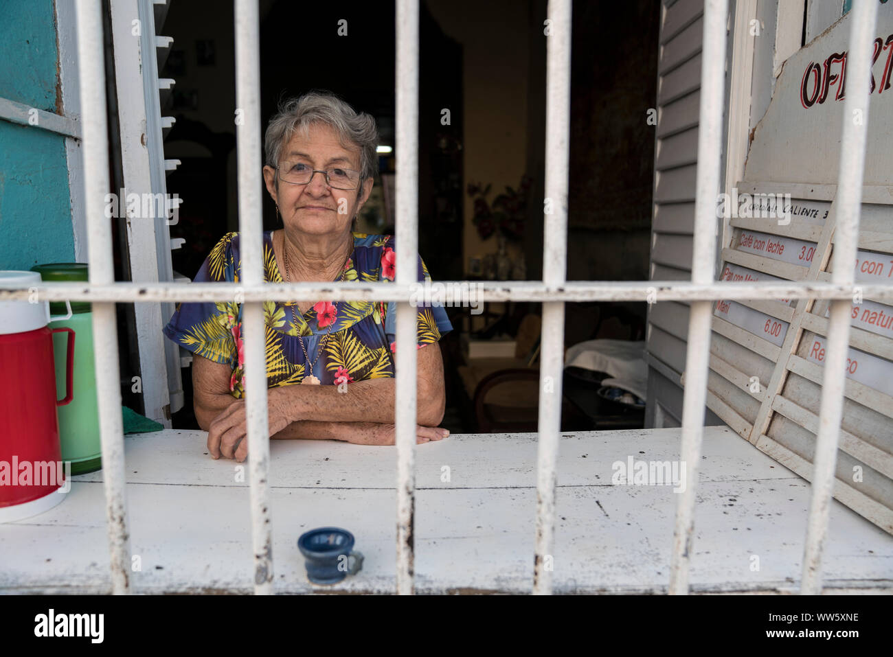 Une femme derrière la fenêtre, le matin elle vend du café, des boissons gazeuses, des jus et des sandwiches, Calle Boca, Trinidad, Cuba Banque D'Images