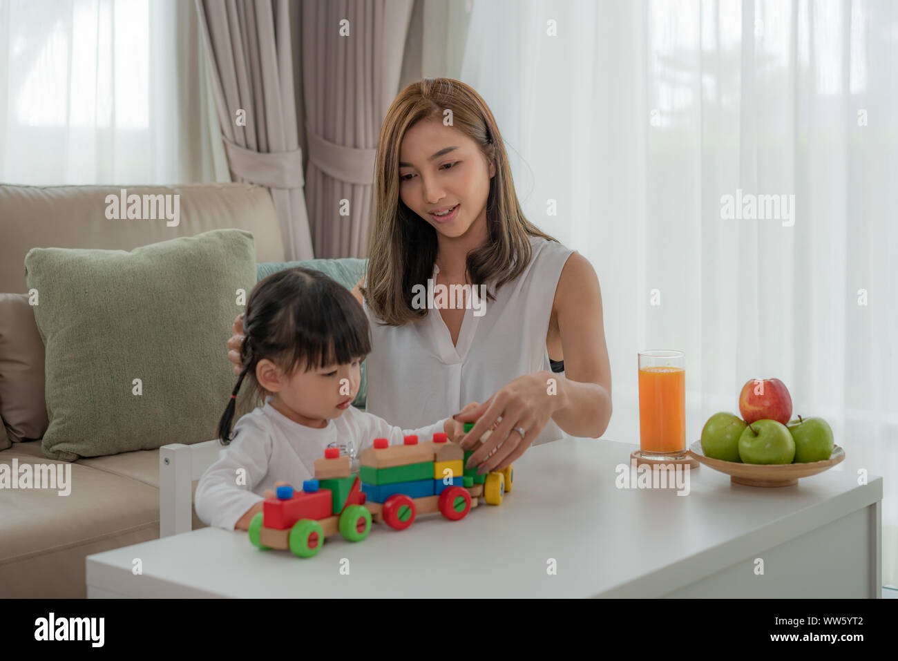 Asian girl avec mère jouer avec des jouets en bois train bloc sur la table à la maison. Banque D'Images