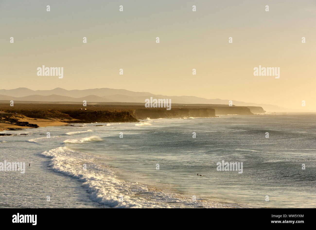 Espagne, Fuerteventura, El Cotillo, côte, mer, plage de sable, la côte escarpée, surf, baigneurs éparpillés, lumière du soir Banque D'Images