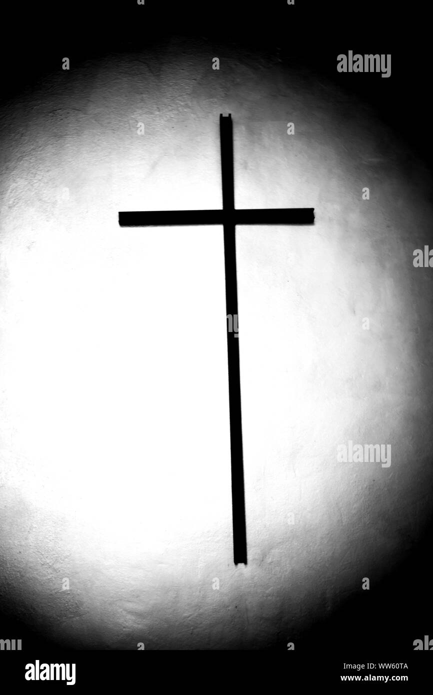 Faisceau de lumière projeté directement sur le milieu d'une croix dans une crypte sombre, Banque D'Images