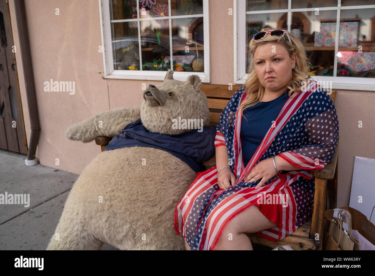 Contrarié, en colère femme portant des vêtements américains patrotic s'assoit et pose avec un ours en peluche. Concept pour grognon, ennuyé, et faisant la moue Banque D'Images