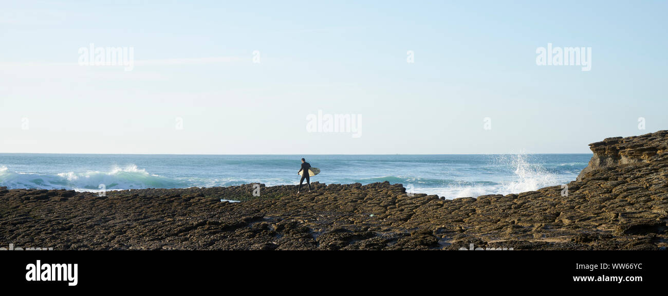 Man carrying surf rock ci-dessus dans les vagues de la mer Banque D'Images