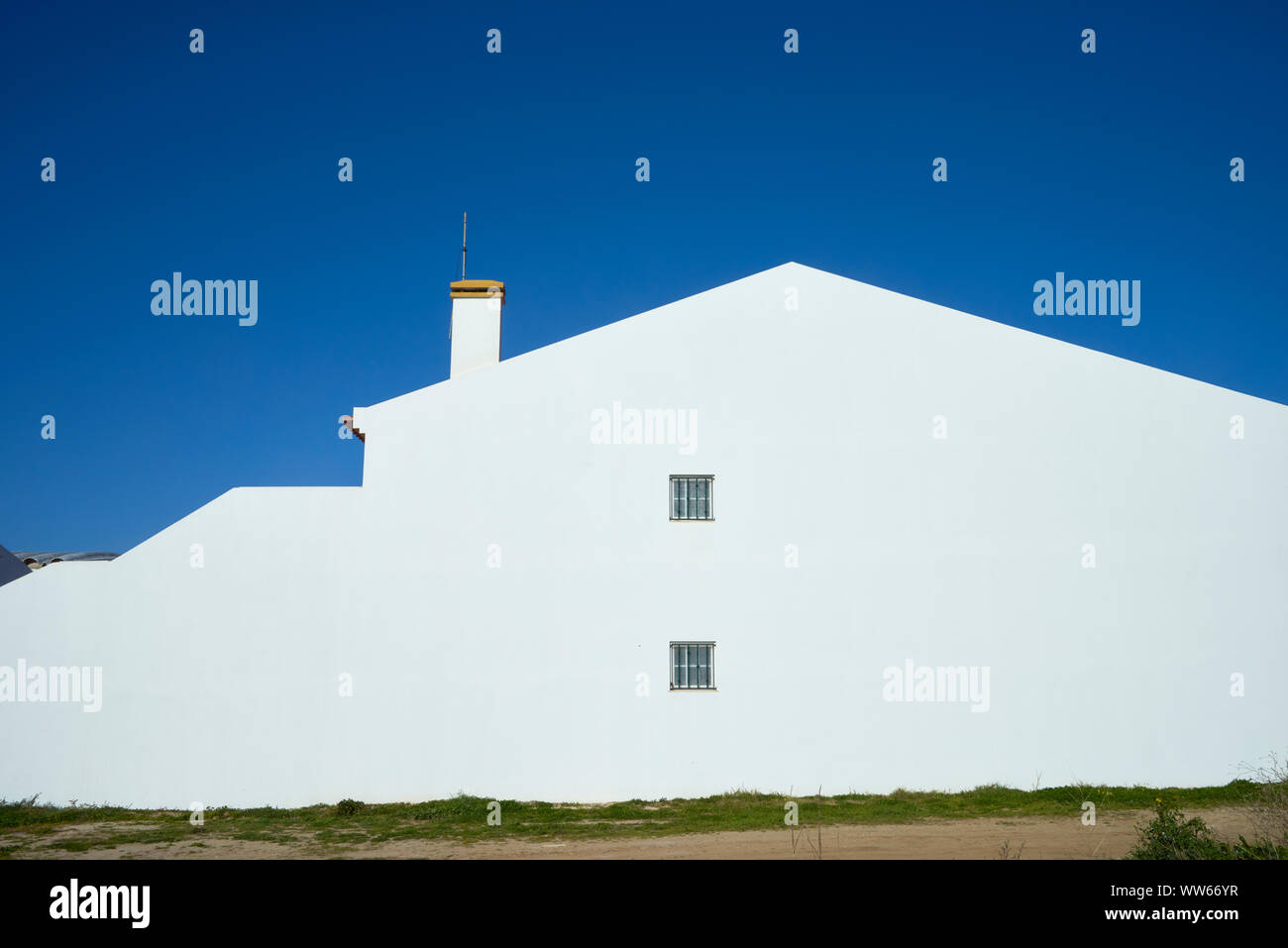 Mur d'une maison blanche avec fenêtre, cheminée et ciel bleu Banque D'Images
