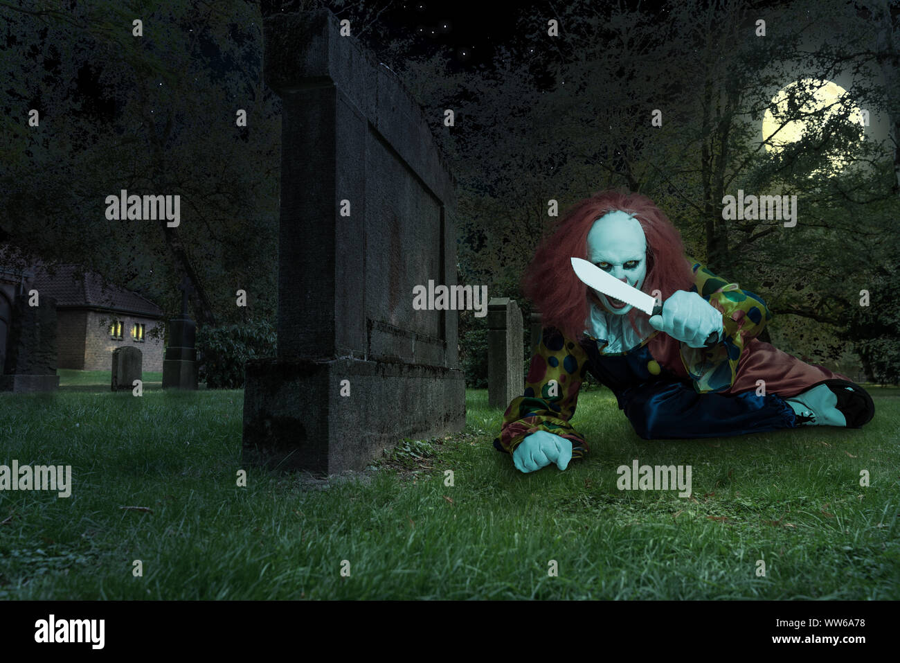 Un clown effrayant avec un couteau sur un cimetière Banque D'Images