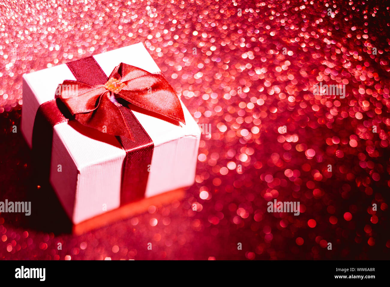 Boîte cadeau de Noël avec fort sur fond rouge étincelaient Banque D'Images