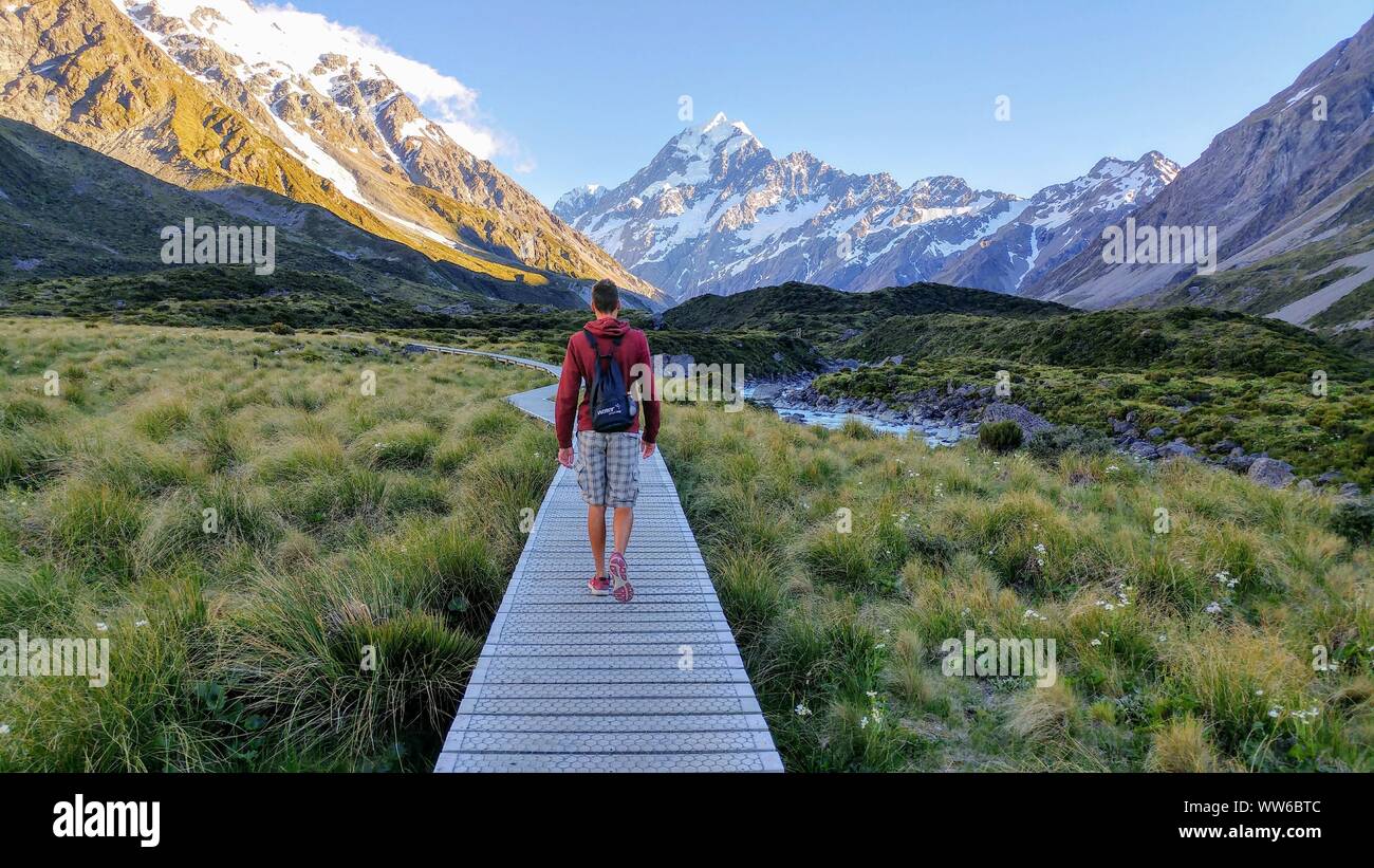 Personne marche sur jetty vers la montagne enneigée sur la Hooker Valley Track en Nouvelle-Zélande Banque D'Images
