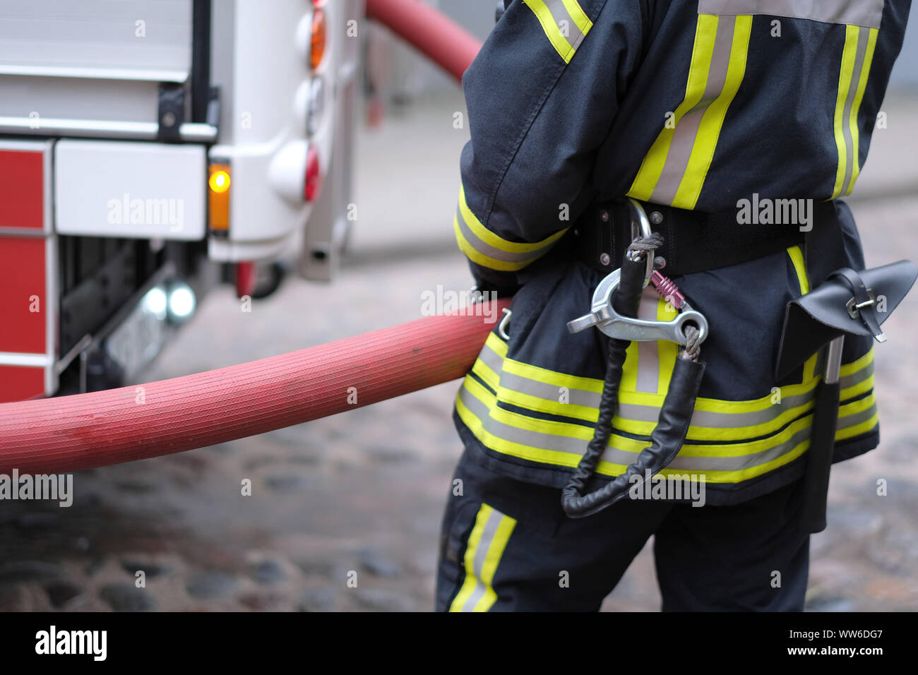 Un membre de la brigade d'incendie est titulaire d'une réserve d'eau flexible de la fire engine Banque D'Images