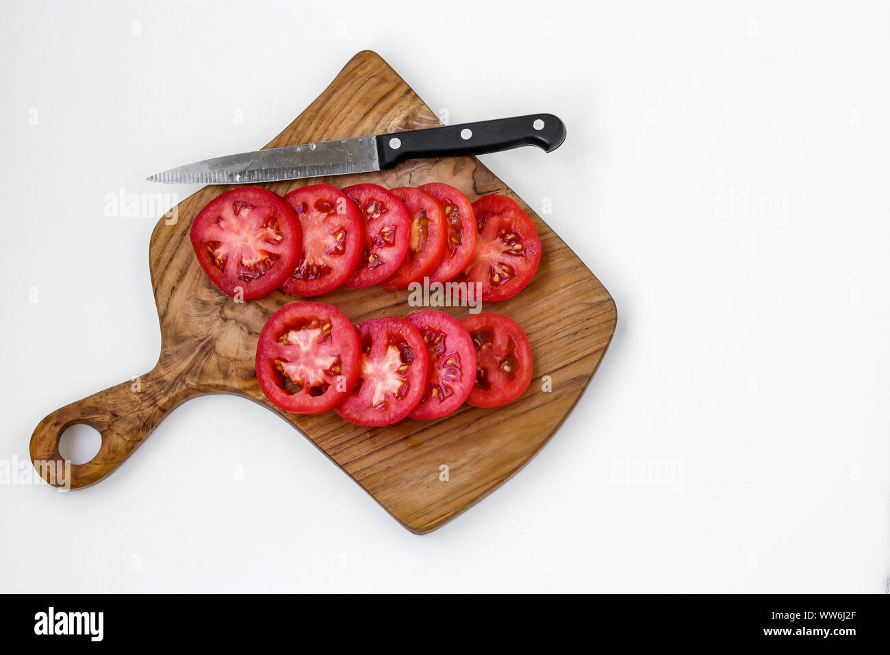 Des tranches de tomate isolé sur une planche en bois sur un fond blanc, copy space Banque D'Images