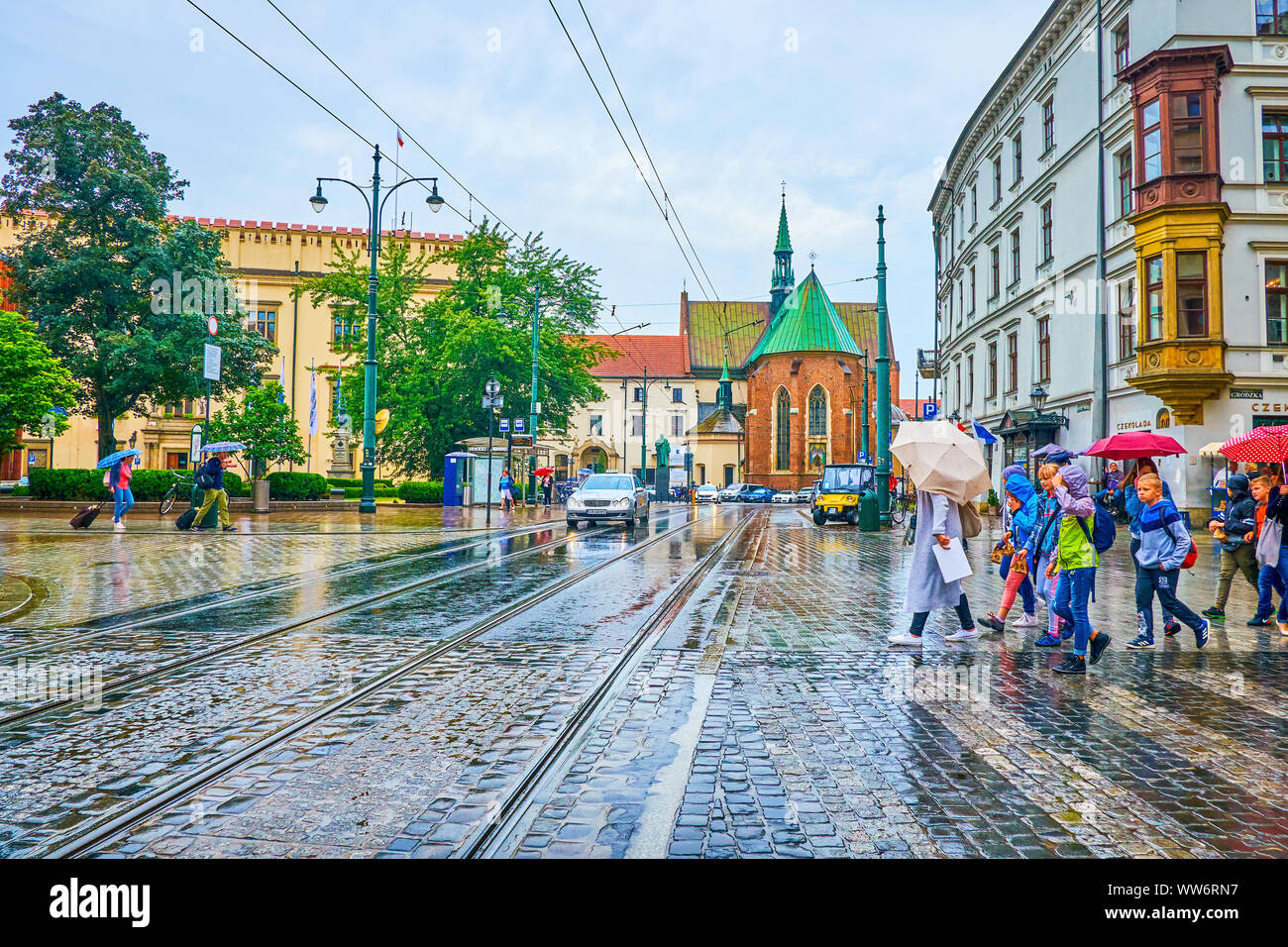 Cracovie, Pologne - 13 juin 2018 : Le groupe d'enfants sous les parasols traverser la route dans tous les Saints Square pendant jour de pluie, le 13 juin à Cracovie Banque D'Images