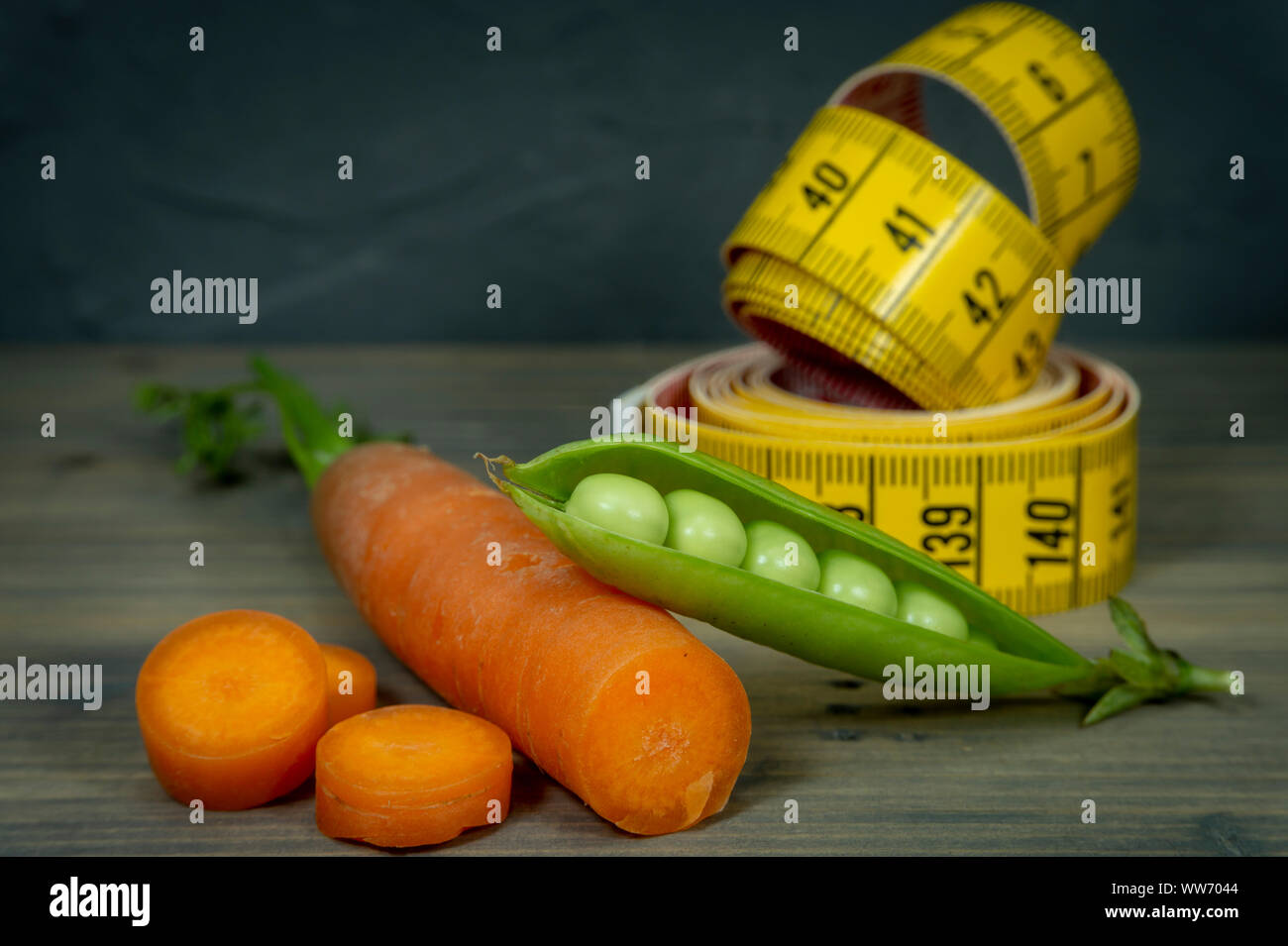 La perte de poids et régime alimentaire sain concept avec carotte, pot de pois et ruban à mesurer sur fond de bois Banque D'Images