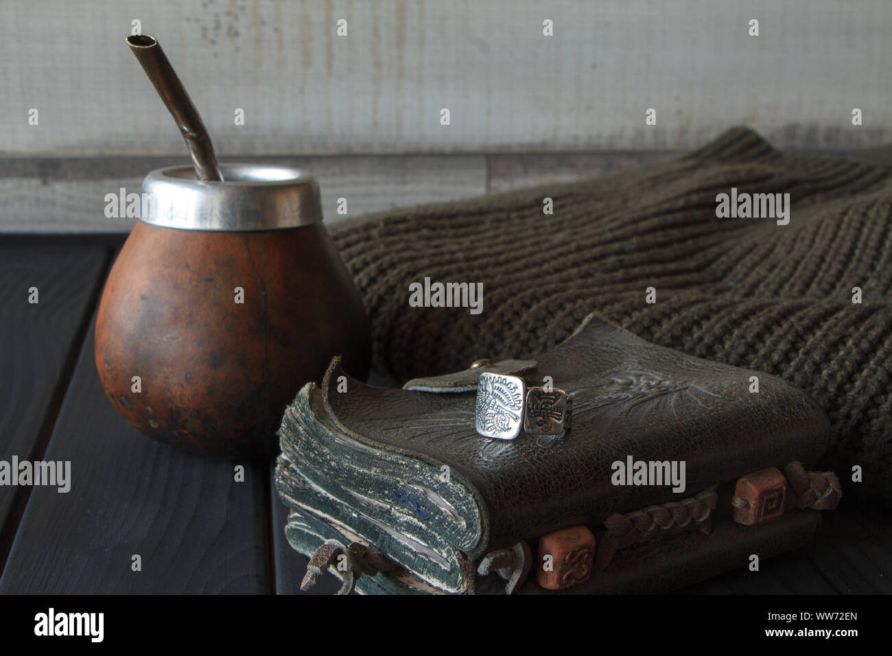 La vie toujours la main de la yerba mate artisanale cuir Gourd Calabash thé avec de la paille, le cuir ordinateur portable, chandail et joint torique sur le tableau peint en noir, séle Banque D'Images