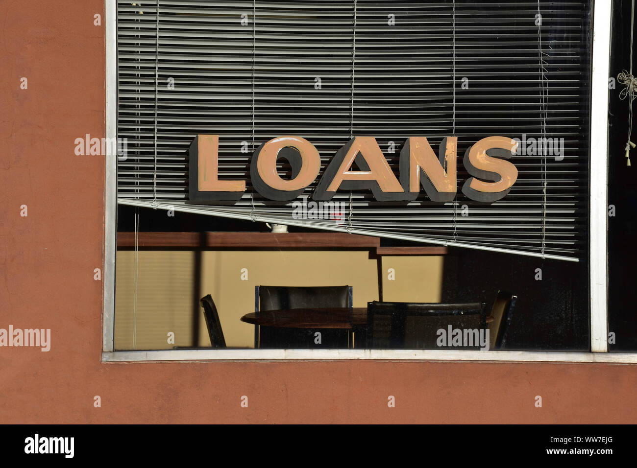 Une scène tranquille dans une petite ville montre un signe de prêts dans la fenêtre d'une boutique de services financiers. Banque D'Images