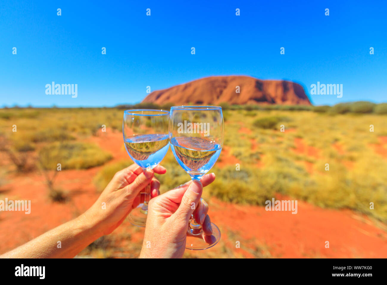 Toast avec deux verres, Centre de l'Australie, Territoire du Nord. Ayers Rock dans le Parc National d'Uluru-Kata Tjuta sur fond flou. Miel à Banque D'Images