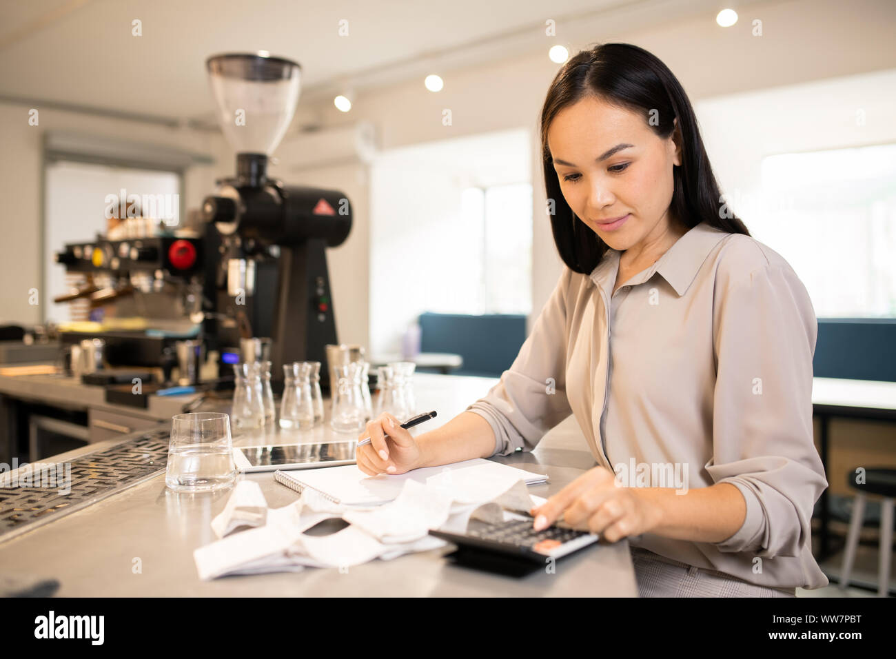 Jolie jeune comptable comptant total des reçus à la fin de journée de travail Banque D'Images
