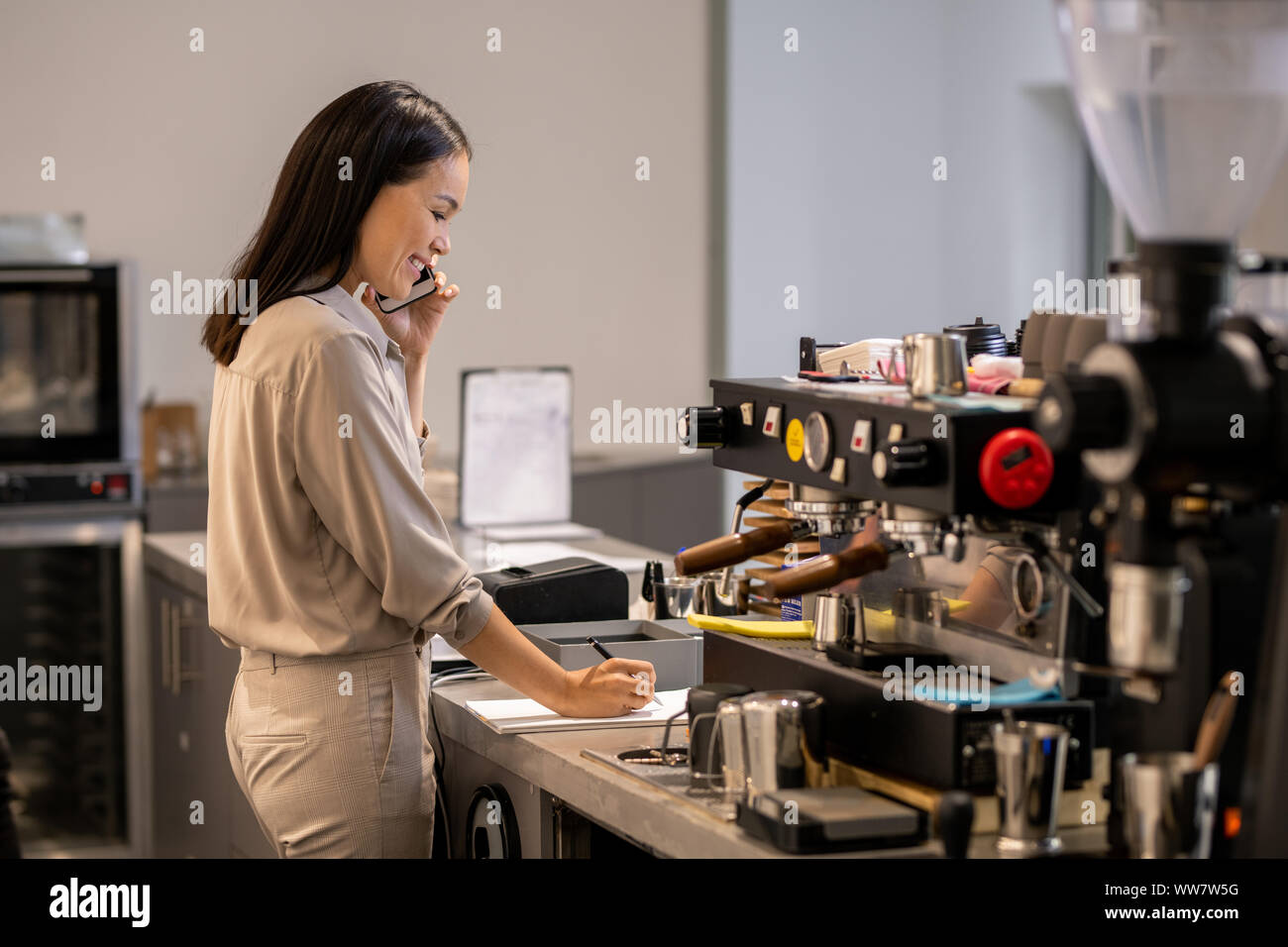 Femme propriétaire d'une cafétéria et de faire appels aux clients notes de travail sur papier Banque D'Images