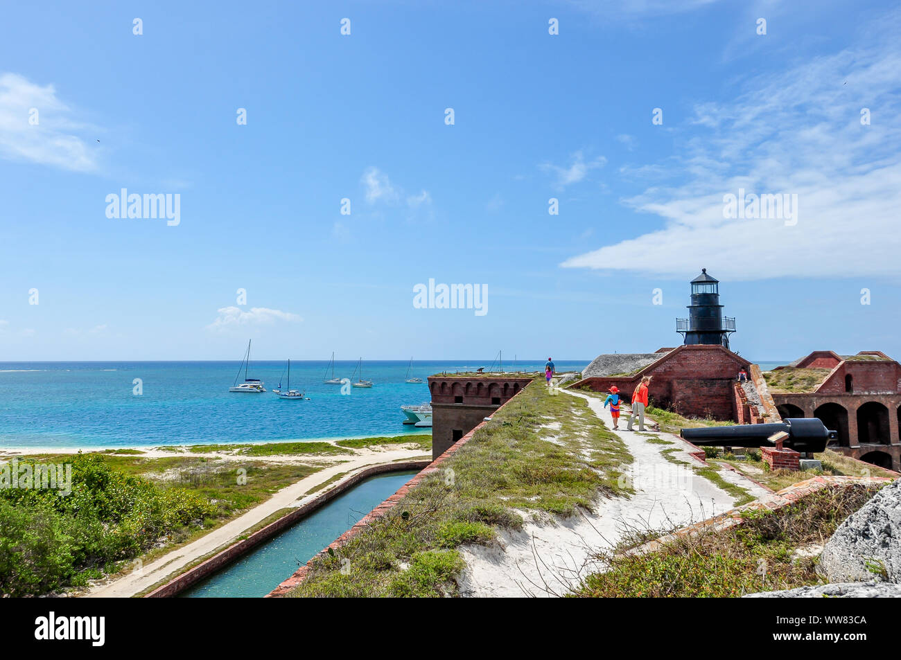 Kids explorer Fort Jefferson à Dry Tortugas National Park avec leur père, marcher le long de la terrasse avec vue sur le phare de l'eau, et des voiliers. Banque D'Images