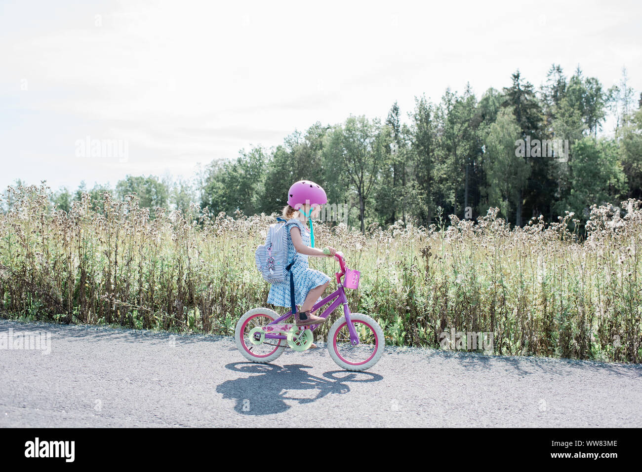 Jeune fille à la maison de l'école à vélo le long d'un chemin de campagne en été Banque D'Images