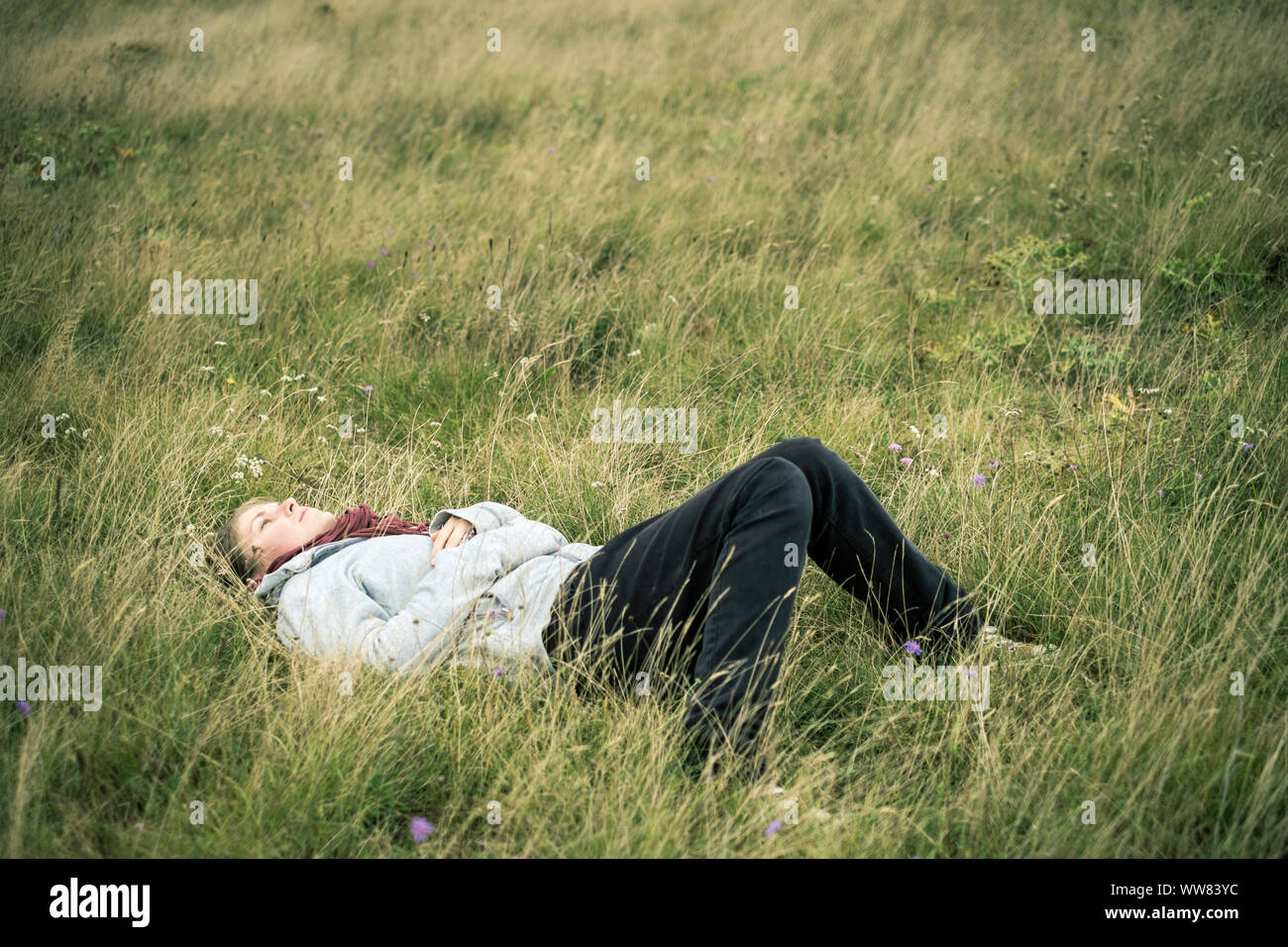 Jeune femme allongé dans l'herbe la rêverie, Dourgne, Tarn, France Banque D'Images