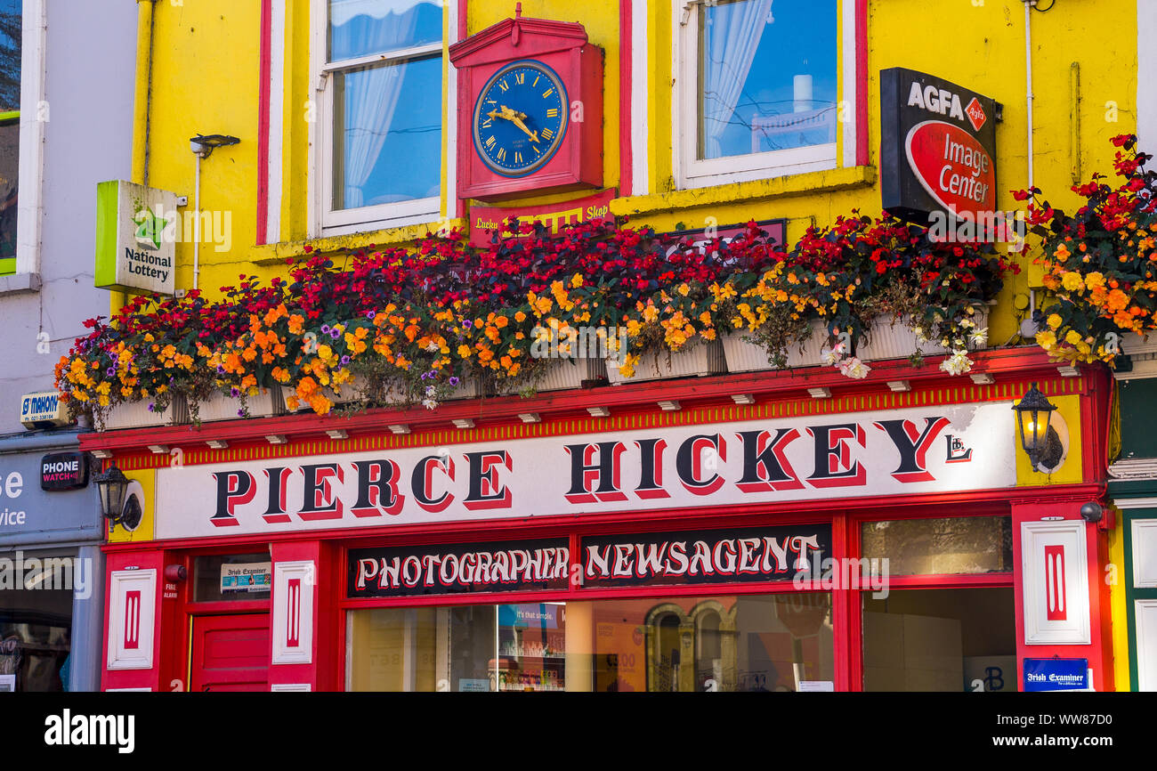 Jaune et rouge fleurs de Bégonia en corbeilles suspendues au-dessus de l'agent actualités shop Skibbereen en Irlande. Banque D'Images Jaune et rouge fleurs de Bégonia en corbeilles suspendues au-dessus de l'agent actualités shop Skibbereen en Irlande. Banque D'Images