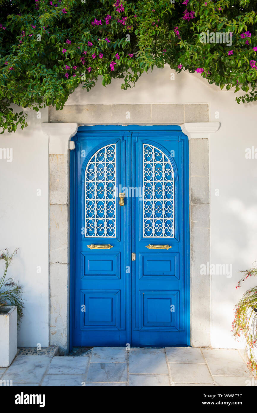 Scène de village méditerranéen typique de murs blanchis à la chaux et porte bleue encadrée par un écrin de verdure dans le village touristique de Bodrum, Turquie Banque D'Images