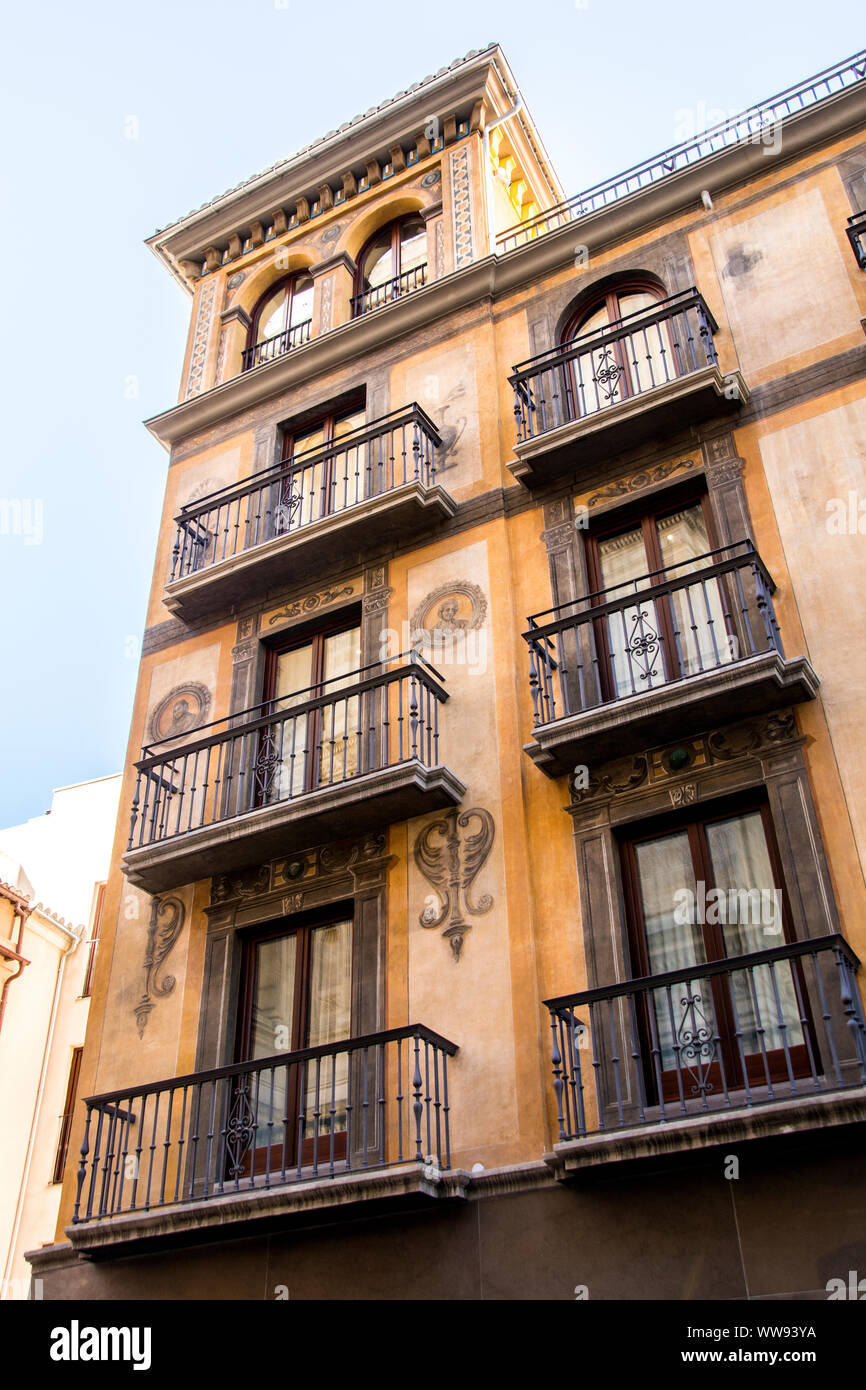 Un grand bâtiment de plusieurs étages aux tons de terre, doté de plusieurs fenêtres avec plomb et d'un balcon. Banque D'Images