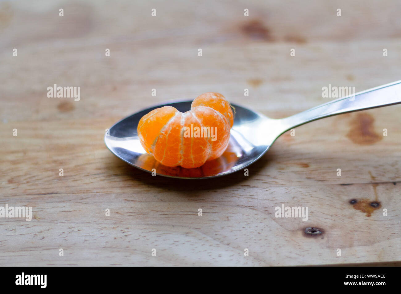 Orange clémentine pelée sur une cuillère montrant le concept d'été, de vie propre, de bien-être et de bien-être Banque D'Images