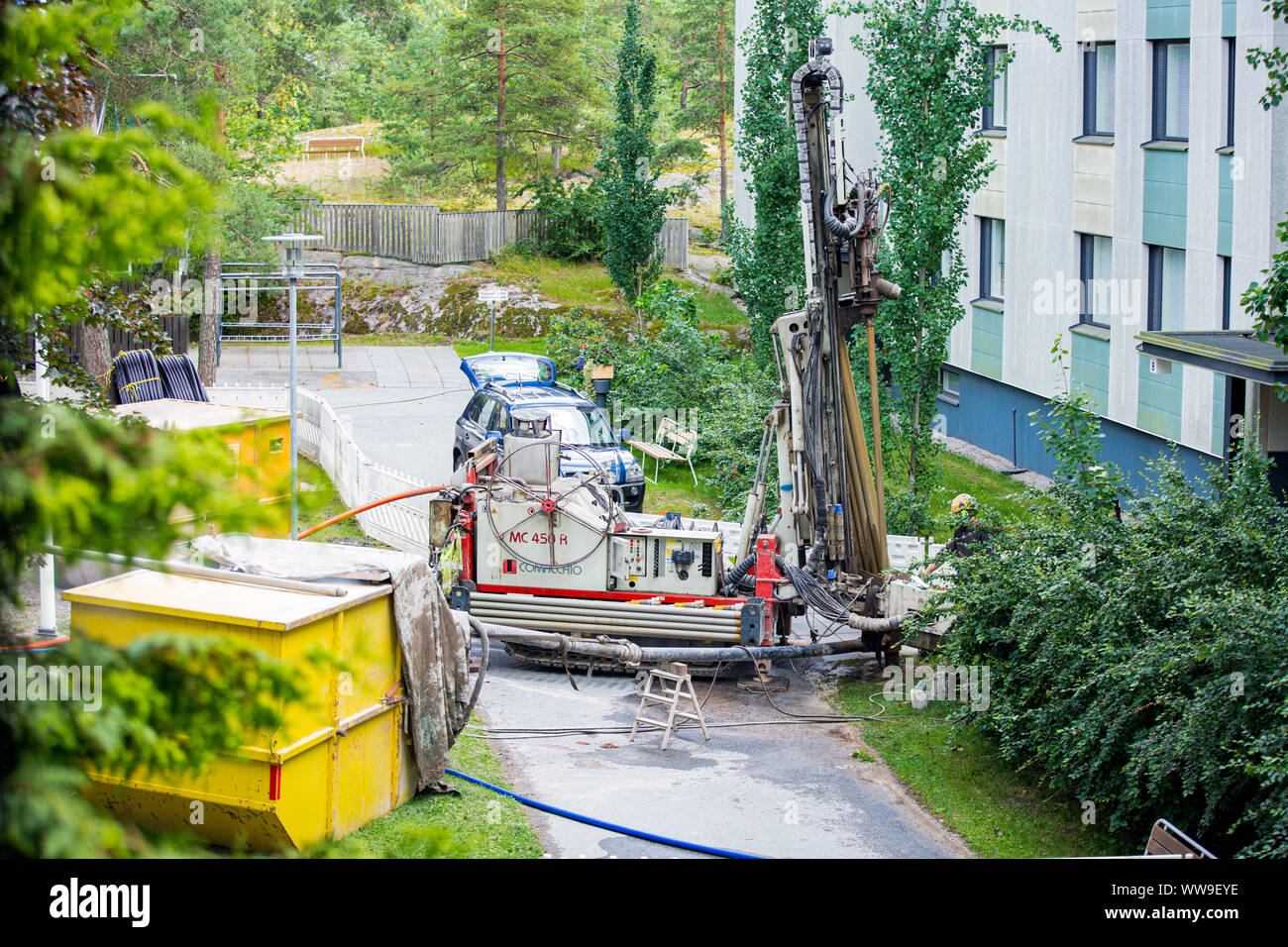Espoo, Finlande : l'installation de pompe à chaleur géothermique en Eco friendly appartement maison. Plateforme de forage dans la cour. Worker in hard hat un forage Forage Banque D'Images