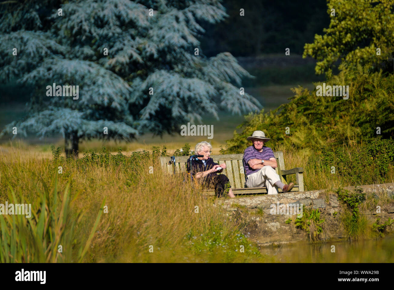 Deux retraités assis sur un banc de parc au bord de l'eau. Banque D'Images