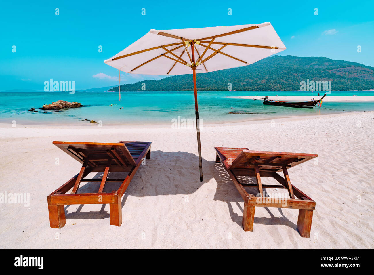 Deux fauteuils chaises sous un parasol sur une plage de sable immaculé de Koh Lipe, Thaïlande donnant sur un océan bleu azur avec un concept de voyage dans l'île Banque D'Images