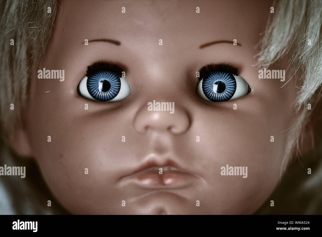 Creepy et dark doll's head. Un visage effrayant d'un blond bébé vintage doll aux yeux bleus Banque D'Images