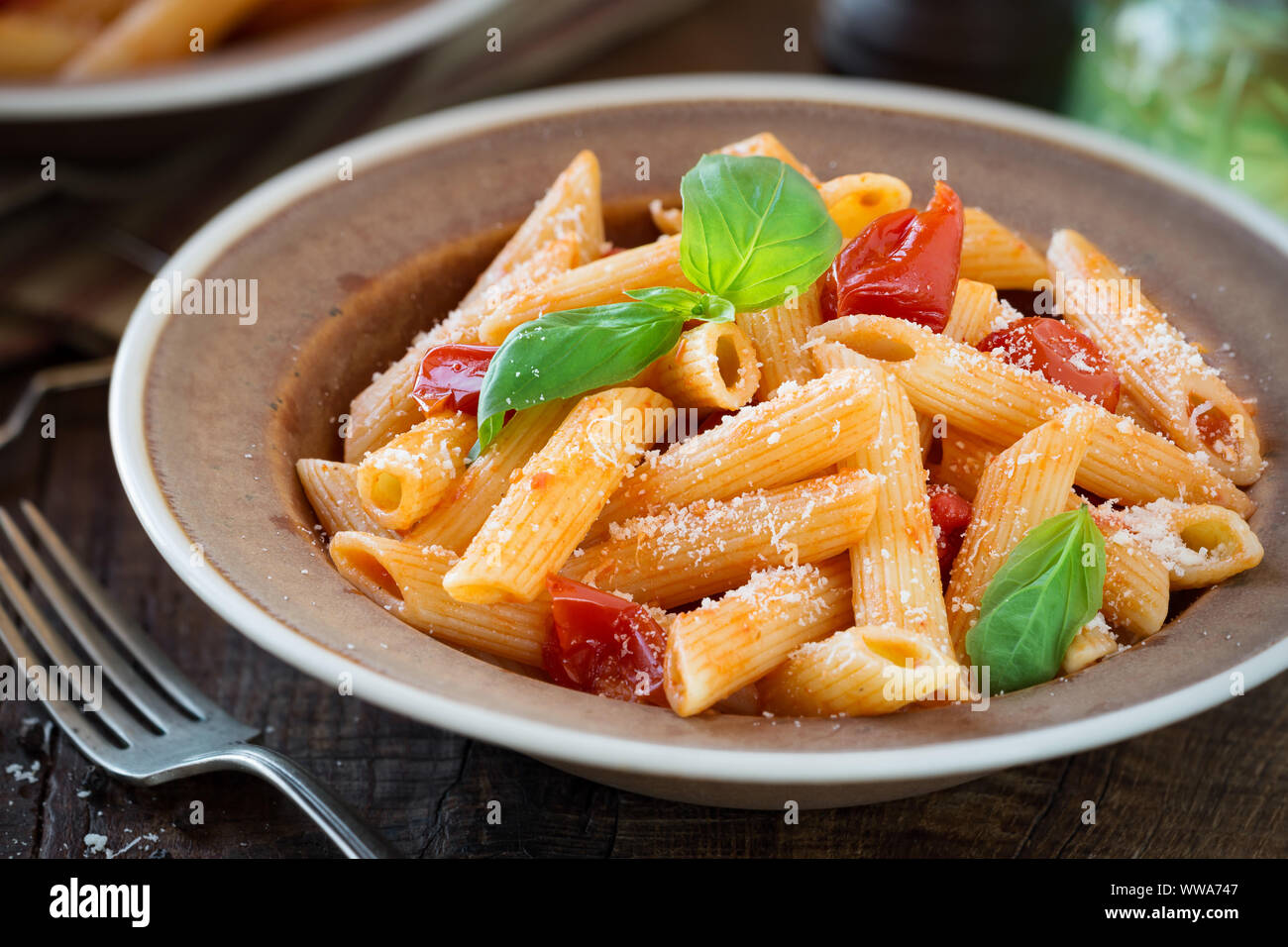 Plat de pâtes penne avec sauce aux tomates cerises, basilic frais et de parmesan râpé - Pasta al Pomodoro. Servi en plaques rustique pour un dîner pour deux Banque D'Images