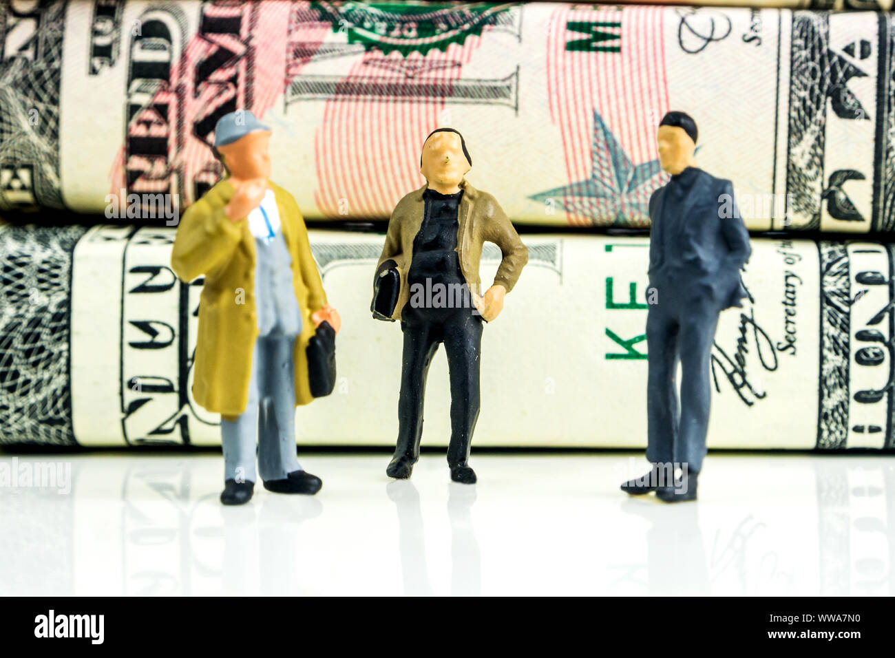 Miniatures de businessmen standing in front of american dollar billets et prendre des décisions économiques sur fond blanc Banque D'Images