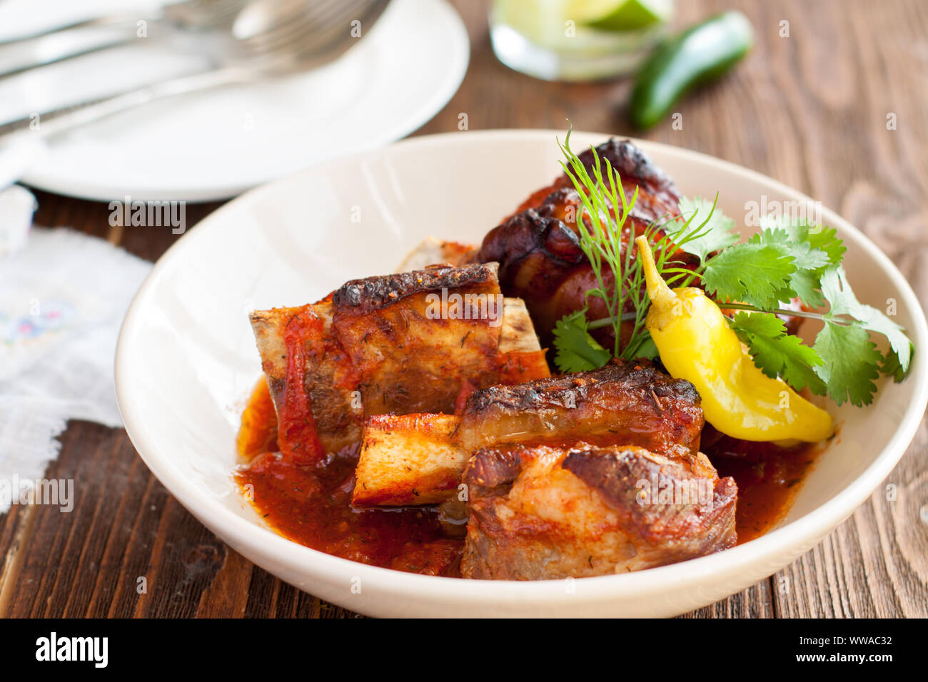 Boeuf braisé aux côtes courtes servi avec du piment jalapeno et herbes fraîches sur planche de bois Banque D'Images