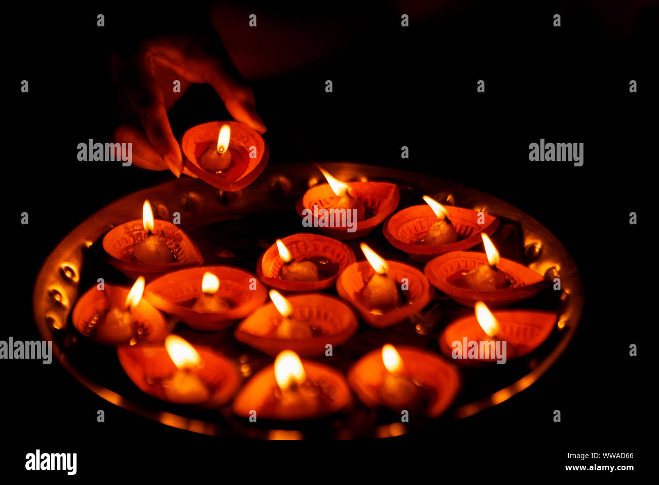 Femme indienne ou girl holding allumé diya traditionnels en argile ou lampe à huile ou une assiette pleine de thali diya pour décoration sur Diwali nuit. Banque D'Images