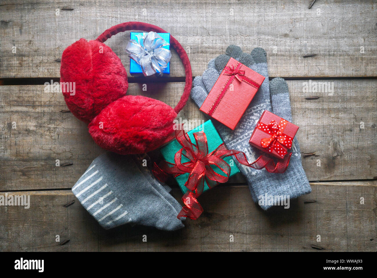 Cache-oreilles et gants gris rouge décorer avec des cadeaux de Noël sur la table de vieux bois Banque D'Images