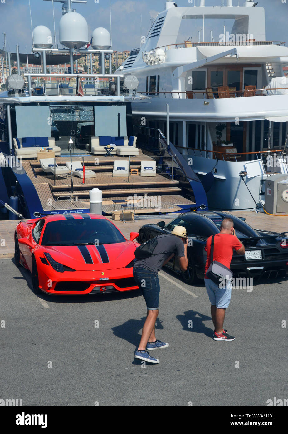 Deux hommes prendre des photos de voitures de sport Parqué par bateau Yacht sur la jetée dans le port de Cannes, Côte d'Azur, France, Union européenne. Banque D'Images