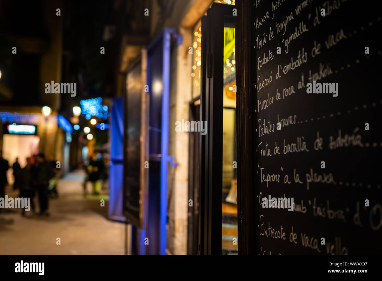 Un restaurant menu du soir dans le Barrio Gotico, avec les piétons flous en arrière-plan. Barcelone, Espagne Banque D'Images