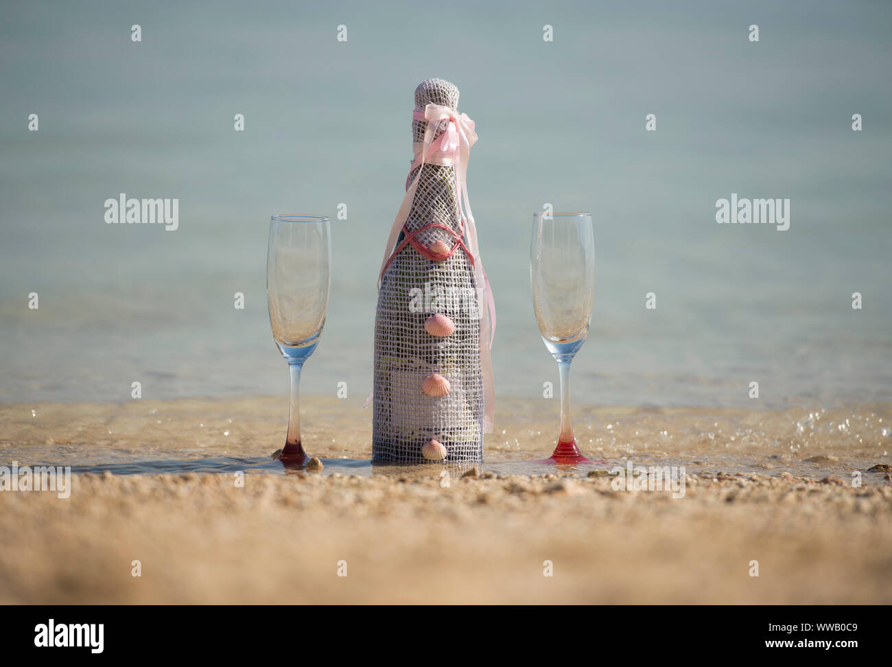 Décorées avec bouteille de champagne et deux verres de vin mousseux de la médecine tropicale et plage de sable à l'eau concept romantique Banque D'Images