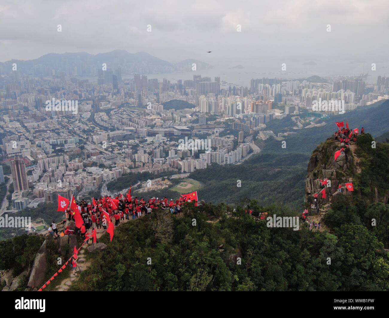 Hong Kong, Chine. 14Th Sep 2019. Vague résidents le drapeau national de la Chine et le drapeau de la Région administrative spéciale de Hong Kong (SAR) au pic du Lion Rock à Hong Kong, Chine du sud, le 14 septembre 2019. Plus de 100 résidents de Hong Kong agité les drapeaux et bannières a tenu à lire 'célébrant le 70e anniversaire de la fondation de la République populaire de Chine" et "topping la violence, se terminant le chaos et le rétablissement de l'ordre' ici le samedi. Credit : Lui Siu Wai/Xinhua/Alamy Live News Banque D'Images