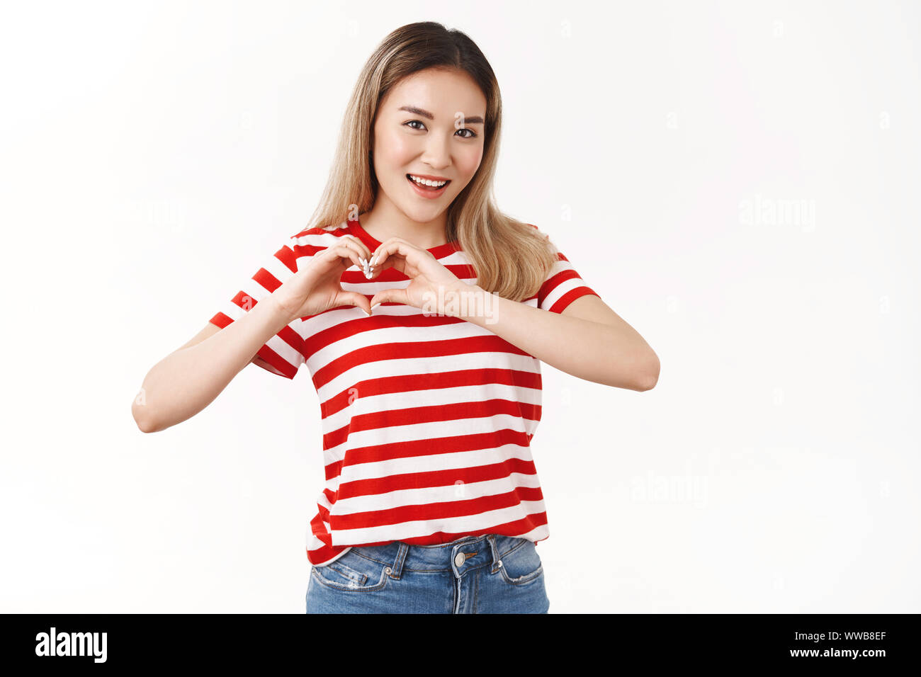 Sassy optimiste bon-à la fille blonde asiatique coeur montrer geste de sympathie à pleines dents sourire excité l'été amie amour romantique chérir Banque D'Images