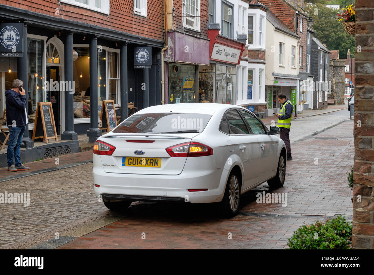 Parking gratuit agent de l'écriture d'un billet pour une voiture stationnée illégalement dans la zone piétonne de la ville. Lewes, Royaume-Uni, Septembre 2019 Banque D'Images