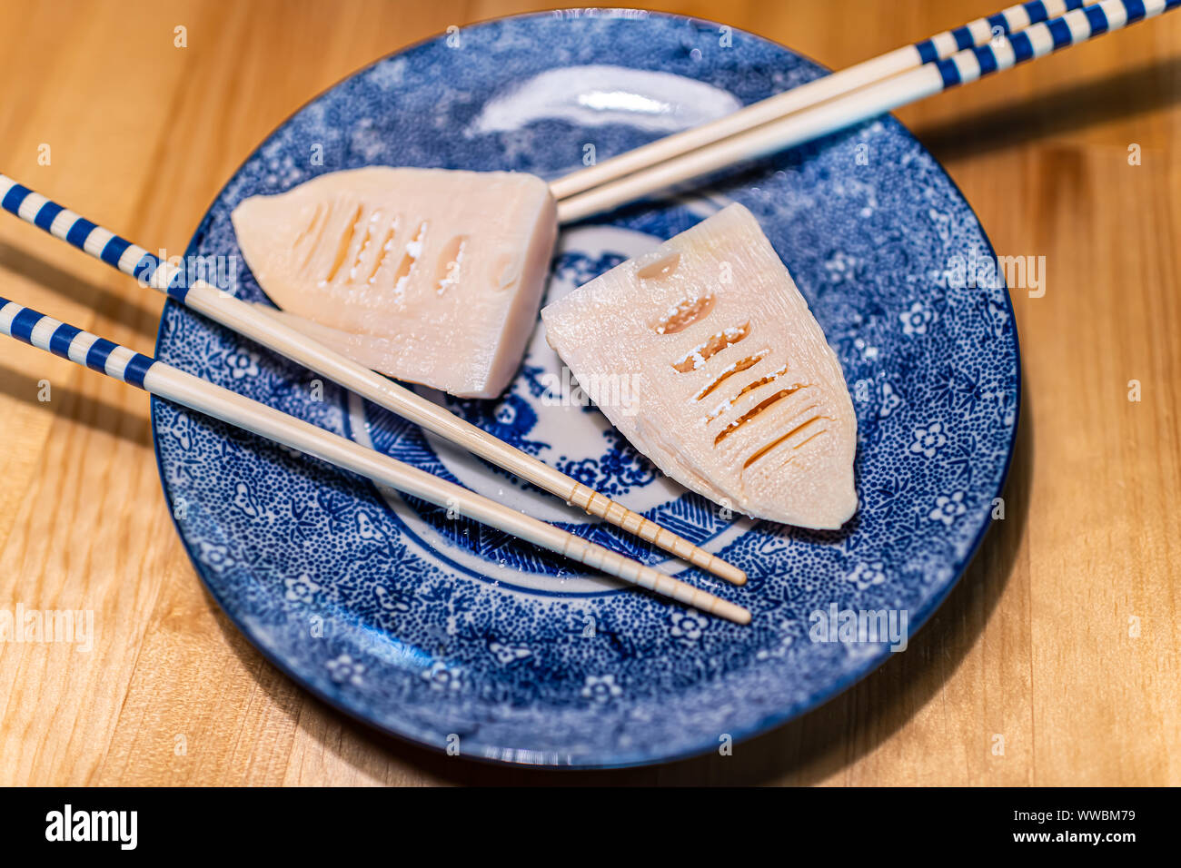 Plaque en céramique bleu traditionnel japonais au restaurant cuisine sur table en bois avec des légumes de printemps takenoko de pousses de bambou par baguettes Banque D'Images