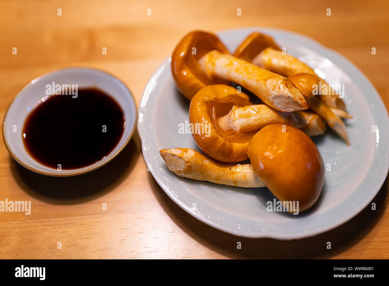 Gros plan du miel cru brut traditionnel japonais champignons sur plaque avec accompagnement de la sauce soja sur la cuisine ou restaurant table en bois Banque D'Images