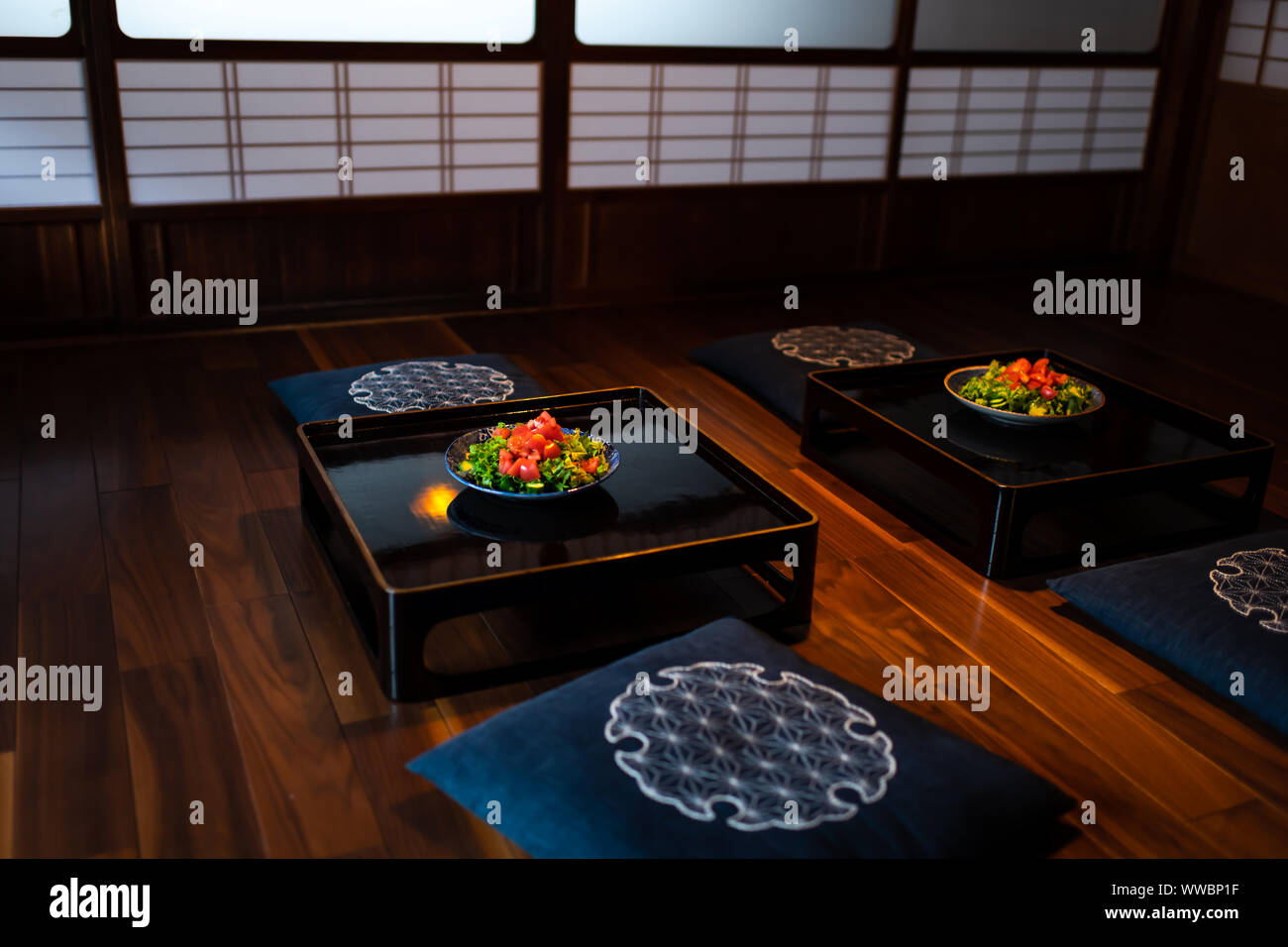 Maison traditionnelle japonaise ou ryokan restaurant chambre avec deux assiettes à salade sur table, coussins coussin avec portes coulissantes shoji en papier de fond Banque D'Images