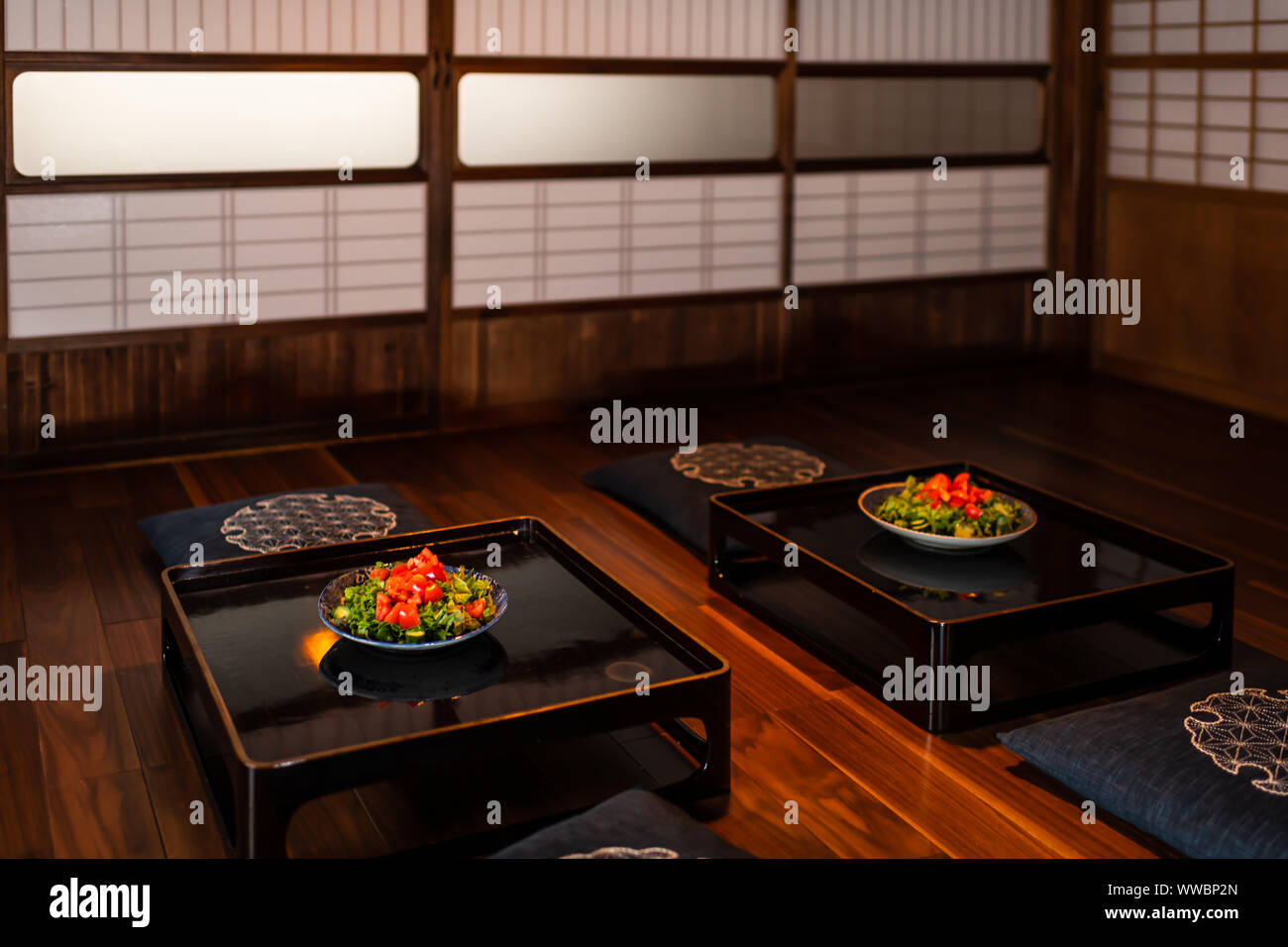 Maison traditionnelle japonaise ou ryokan restaurant chambre avec deux plaques salade de laitue verte sur la table, coussins coussin avec portes coulissantes shoji en papier b Banque D'Images