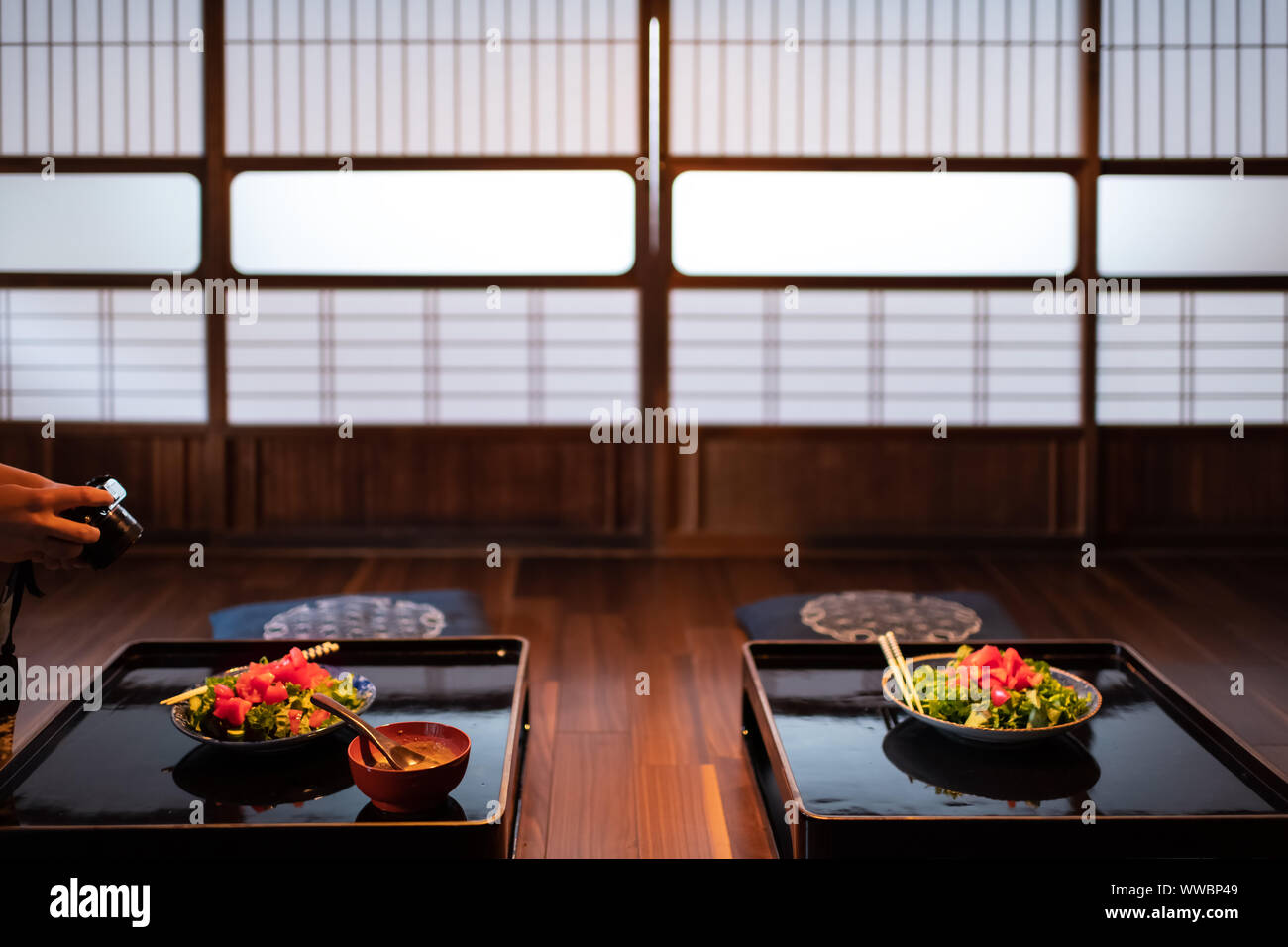 Femme photographe de prendre en photo la maison traditionnelle japonaise ou salle de restaurant ryokan de baguettes, salade de laitue verte deux plaques sur table avec sh Banque D'Images