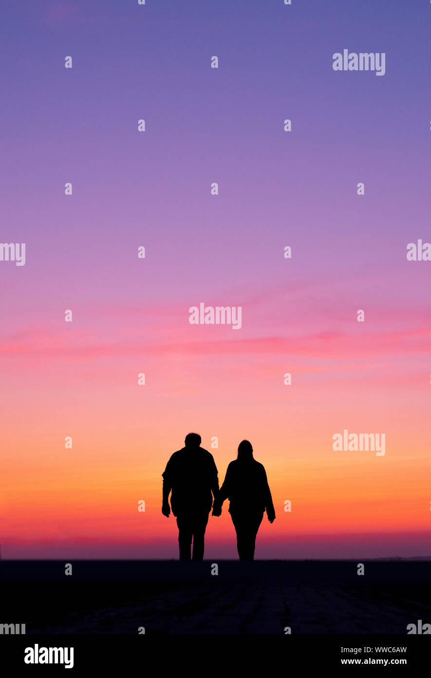 Silhouette de l'homme et la femme à pied en tenant les mains de soleil colorés Banque D'Images